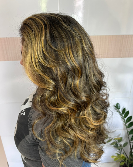 Cabelo loiro ondulado visto de costas com raiz esfumada